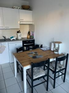 a kitchen with a wooden table and chairs at 2 pièces avec jardin Fleur Marine bord de mer Cabourg in Cabourg