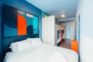 a bedroom with a white bed with an orange and blue wall at Kabannas Liverpool in Liverpool