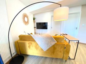 a living room with a yellow couch and a lamp at L'Essentiel - Cocon lumineux au cœur de Hauteville in Hauteville-Lompnes