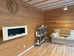 a living room with wooden walls with a tv and a couch at L'écolodge de Laeti in Lunéville