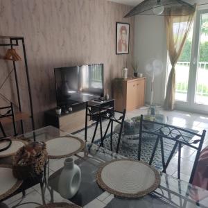 a living room with a glass table and chairs and a television at Au nid carolo in Charleville-Mézières