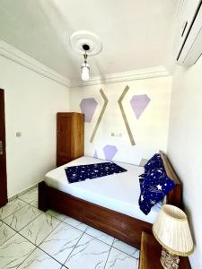 a bedroom with a bed with purple decorations on the wall at Studio B4 B-ssadi Santa Lucia wifi canal gardien in Douala