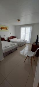 een kamer met twee bedden en een stoel erin bij HOTEL 507 INN in Mejillones