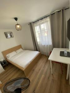 a small bedroom with a bed and a table at G-Logement-Francilien Aéroport CDG, Parc des expositions Villepinte, Bourget, Astérix. in Goussainville +69 photos