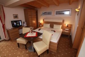 a bedroom with a bed and a table and chairs at Pension Edelweiss in Breitenbach am Inn