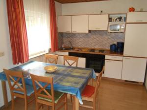 a kitchen with a table and chairs and a kitchen with white cabinets at Kinderfreundliches-Ferienhaus-mit-grosser-Spielwiese in Marktgraitz