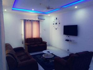 a living room with two couches and a flat screen tv at Phil homes in Accra