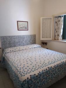 - une chambre avec un lit doté d'un couvre-lit bleu et d'une fenêtre dans l'établissement Casa Pomelia, à Vulcano