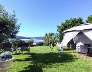 a lawn with chairs and an umbrella and a lake at Casa Mar de Fondo in A Telleira