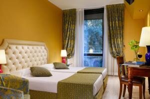 a hotel room with two beds and a window at Hotel Pierre Milano in Milan