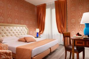 a bedroom with a bed and a desk and a chair at Hotel Pierre Milano in Milan