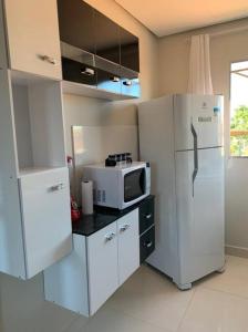 a kitchen with a white refrigerator and a microwave at kitnet208 No centro,c linda vista , tv smart e ar in Montes Claros