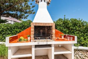 a fireplace on top of a building with trees at Binifortu in Punta Prima
