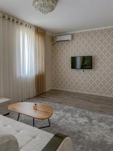 a living room with a couch and a table and a tv at Oasis Residence Fergana in Fergana