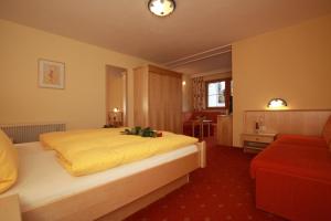 a bedroom with a large bed and a red couch at Pension Edelweiss in Breitenbach am Inn +40 photos