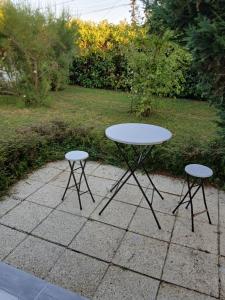 a white table and two stools on a patio at Jolie maison in Gurgy