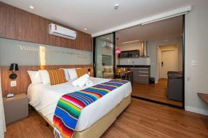 Apartamento sofisticado Campos do Jordão في كامبوس دو جورداو: غرفة نوم مع سرير كبير مع بطانية ملونة