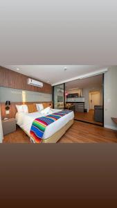 Apartamento sofisticado Campos do Jordão في كامبوس دو جورداو: غرفة نوم كبيرة مع سرير كبير وغرفة معيشة