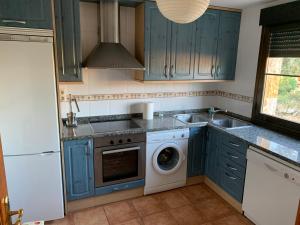 a kitchen with blue cabinets and a washing machine at Casa Enrique Soria in Santervás de la Sierra