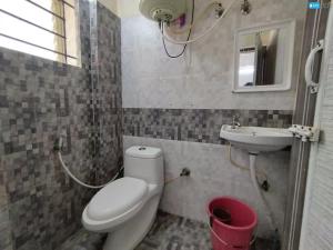 a bathroom with a toilet and a sink at Hotel Anugraha in Kalyānpur