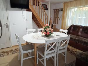a white table with chairs and a vase of flowers on it at JJ Zavoi in Orăştie