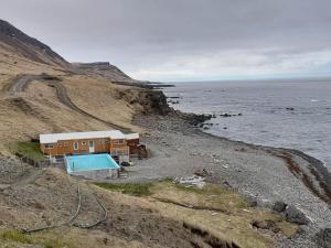 a house on the side of a cliff next to the ocean at Bergistangi Apartment in Norðurfjörður
