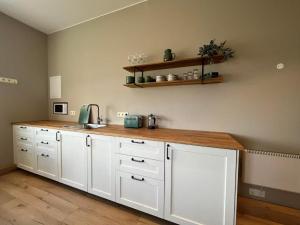 a kitchen with white cabinets and a wooden counter top at Bergistangi Apartment in Norðurfjörður