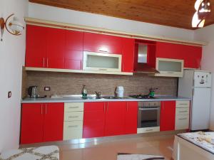 a red kitchen with white appliances and red cabinets at Sara Guesthouse in Berat +27 photos