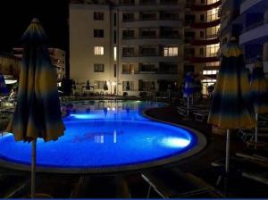 a large swimming pool with umbrellas next to a building at Central Plaza Apartment in Sunny Beach +3 photos
