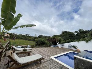 a wooden deck with a swimming pool next to a house at Trancoso Villa Nobre in Trancoso