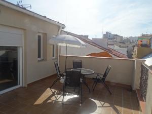 un patio con mesa, sillas y sombrilla en Málaga Apartamentos - Nuño Gómez, 24, en Málaga