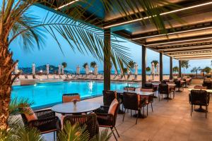 a restaurant with tables and chairs next to a swimming pool at Elite World Kuşadası in Kuşadası