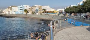 a group of people standing on a sidewalk near the water at Casa Magec in Arinaga