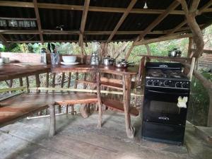 a wooden table with a stove and a table with benches at Casa del musgo y helecho in Minca