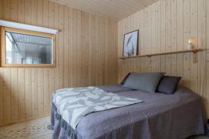 a bedroom with a bed in a wooden wall at Villa Kuusi by HiYlläs in Äkäslompolo
