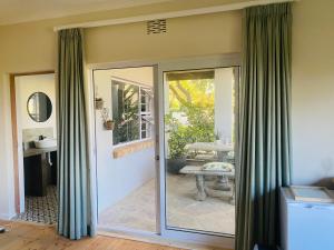 a sliding glass door with green curtains in a room at Winelands guest room in Stellenbosch