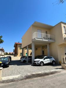 two cars parked in a parking lot in front of a building at Hotel Perla in Castiglione della Pescaia
