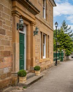 a green door on the side of a brick building at The Old Bank House Self Catering Apartment Dornoch in Dornoch
