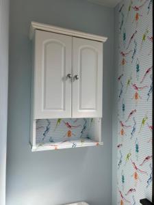 a white cabinet in a bathroom with a colorful wallpaper at Welcome to Camp Sycamore in Pittsburgh +11 photos