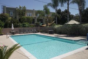 basen z krzesłami i parasolem obok budynku w obiekcie Harbor Inn & Suites w mieście Anaheim