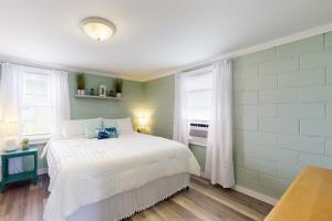 a bedroom with a white bed and two windows at Miller Time in Atlantic Beach