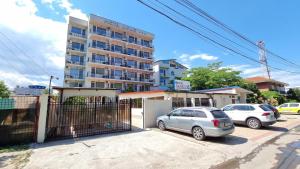 Dos coches estacionados en un estacionamiento frente a un edificio. en Hotel Impact, en Costinesti