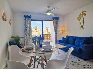 Una sala de estar con un sofá azul y una mesa y sillas. en Fairways Club - TEIDE VIEW OASIS - heated pool, family apt, en San Miguel de Abona