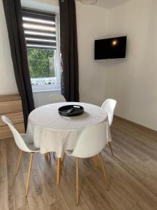 a white table with white chairs and a plate on it at Studio 1er étage - Centre-ville - Local vélos disponible in Mayenne