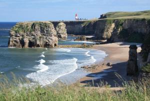 a view of a beach with a lighthouse on a cliff at The Imeary - Vacant Nests in Westoe