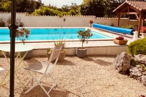 a white chair and a table and a swimming pool at 4 bed home with private pool in Génouillé