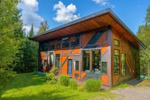 ein Haus mit vielen Fenstern im Gras in der Unterkunft The Sculptural Nature Escape, hot tub, Billiards in Val-David