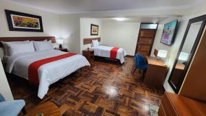 una camera d'albergo con due letti e una scrivania di INCA PALACE EXPERIENCE Hotel a Puno