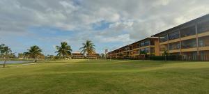 a large building with a grass field in front of it at Apartamento no Villa das Águas in Estância