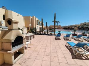 a patio with lounge chairs and a fireplace next to a pool at Castillo Mar - 82 in Caleta De Fuste